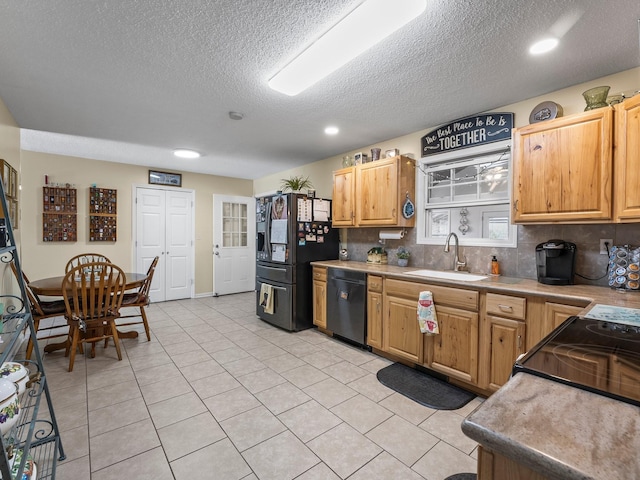 kitchen featuring light tile patterned floors, tasteful backsplash, light countertops, a sink, and black appliances