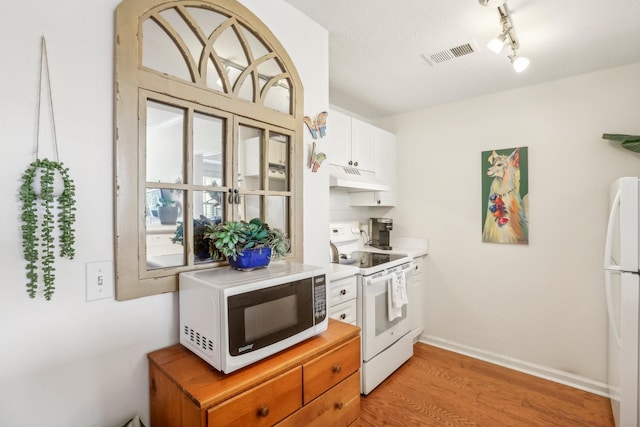 kitchen with white appliances, light wood finished floors, visible vents, light countertops, and under cabinet range hood