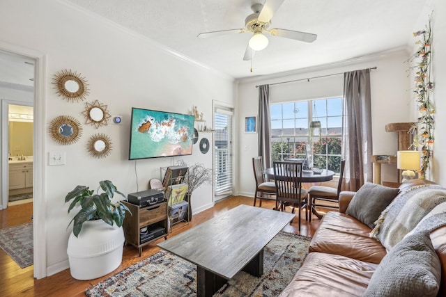 living room with baseboards, ceiling fan, ornamental molding, and wood finished floors