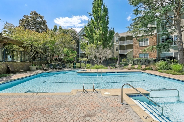 community pool with a patio area and fence