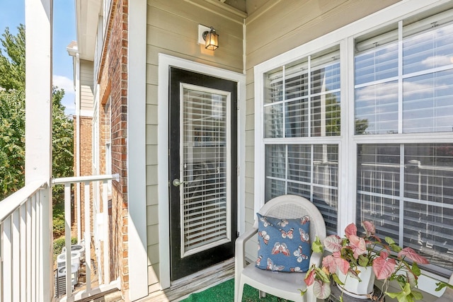 view of exterior entry with brick siding and central AC unit