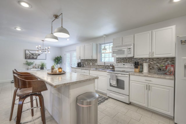 kitchen featuring hanging light fixtures, white appliances, white cabinets, and a center island