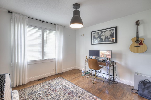 office featuring visible vents, a textured ceiling, baseboards, and wood finished floors