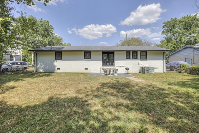 rear view of property featuring crawl space, brick siding, a yard, and a patio