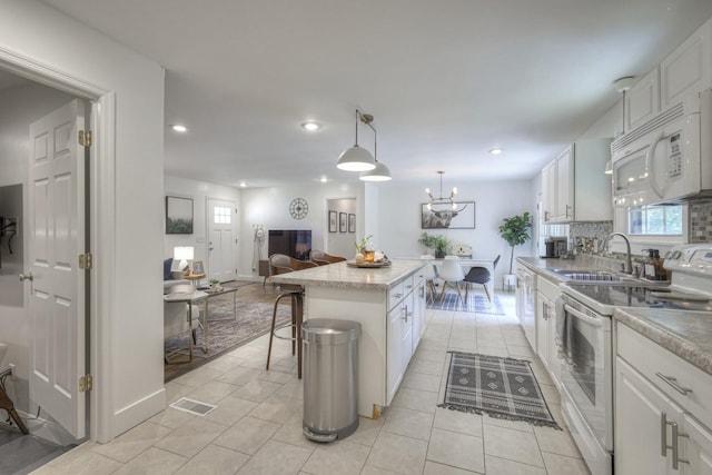 kitchen featuring white appliances, a kitchen island, white cabinetry, and decorative light fixtures