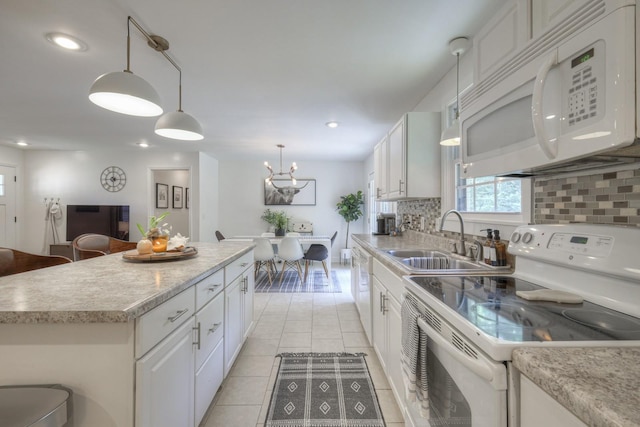 kitchen featuring white appliances, white cabinets, light countertops, a center island, and decorative light fixtures