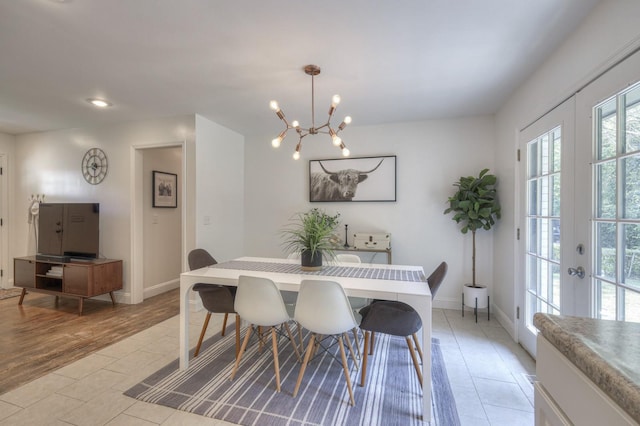 dining room featuring light wood-type flooring, baseboards, a chandelier, and french doors