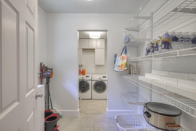 laundry room featuring light tile patterned floors, washer and clothes dryer, cabinet space, and baseboards