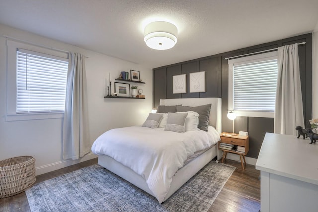 bedroom featuring dark wood finished floors, a textured ceiling, and baseboards