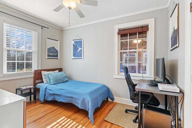 bedroom featuring ornamental molding, light wood-type flooring, baseboards, and a ceiling fan