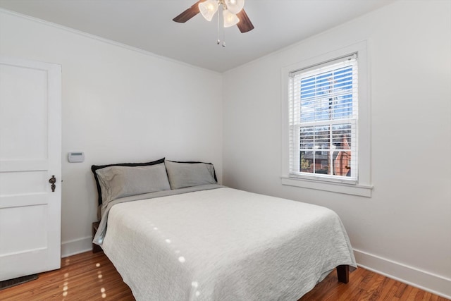 bedroom featuring a ceiling fan, baseboards, and wood finished floors