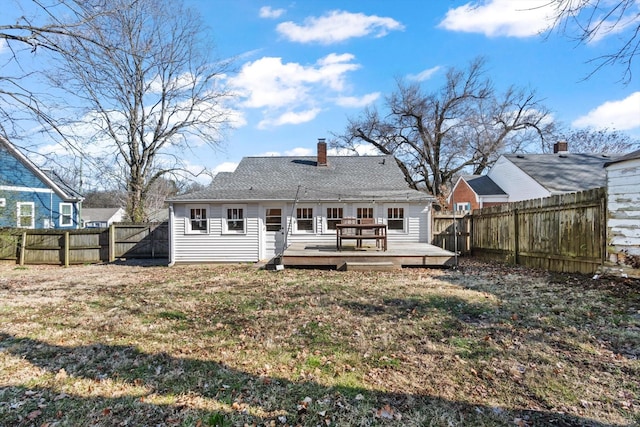 back of house featuring a chimney, a fenced backyard, a lawn, and a deck