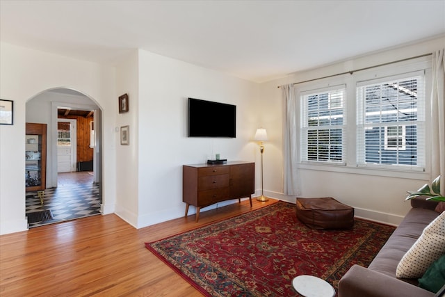 living room featuring arched walkways, wood finished floors, and baseboards