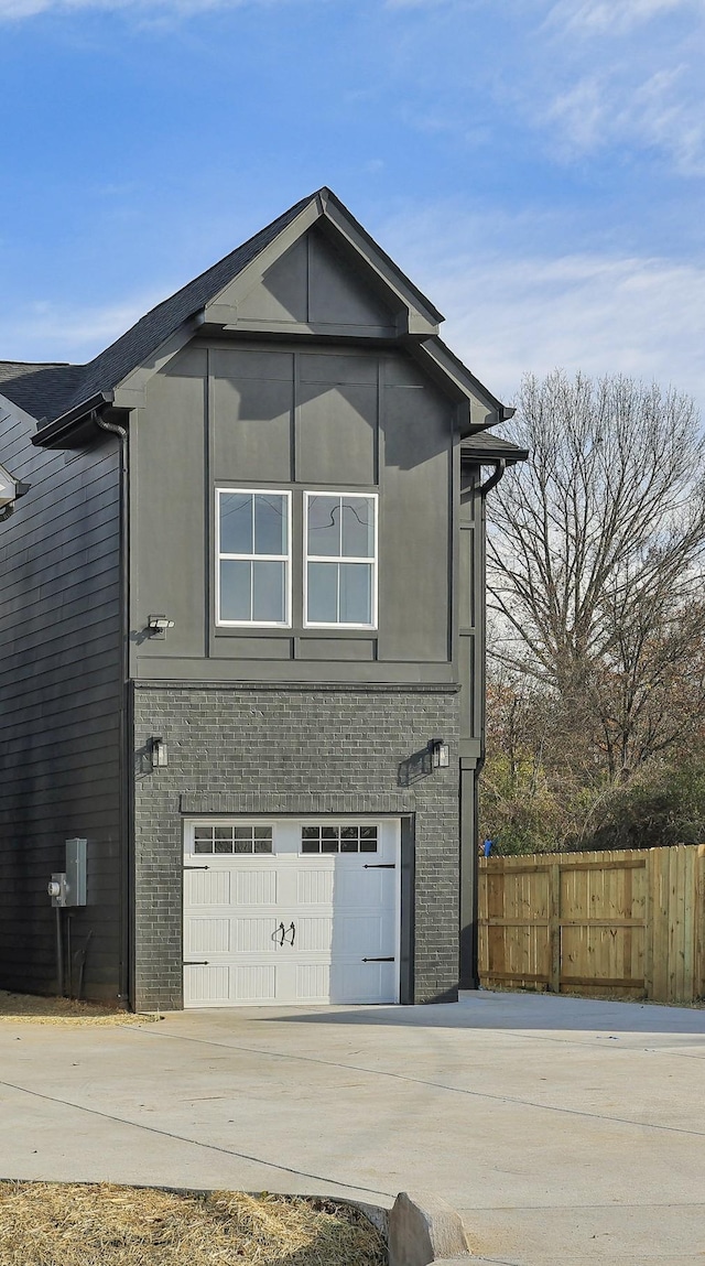 exterior space with a garage, brick siding, fence, concrete driveway, and stucco siding