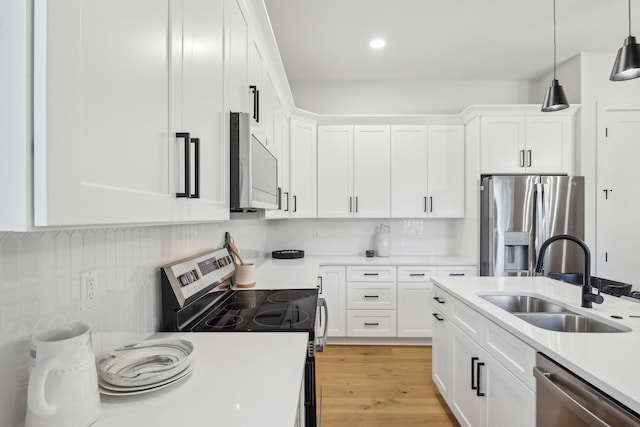 kitchen with a sink, stainless steel appliances, light countertops, and white cabinets