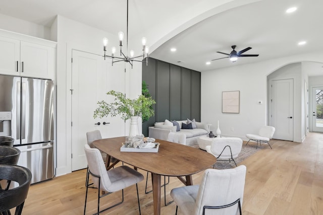 dining space featuring light wood finished floors, ceiling fan with notable chandelier, arched walkways, and recessed lighting