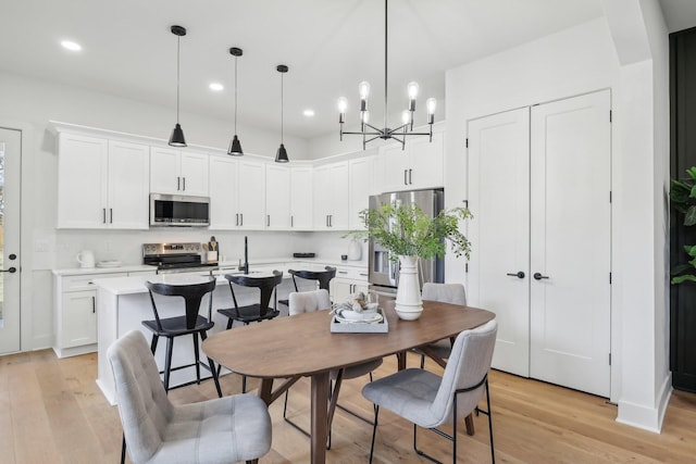 dining area featuring light wood-type flooring, an inviting chandelier, and recessed lighting