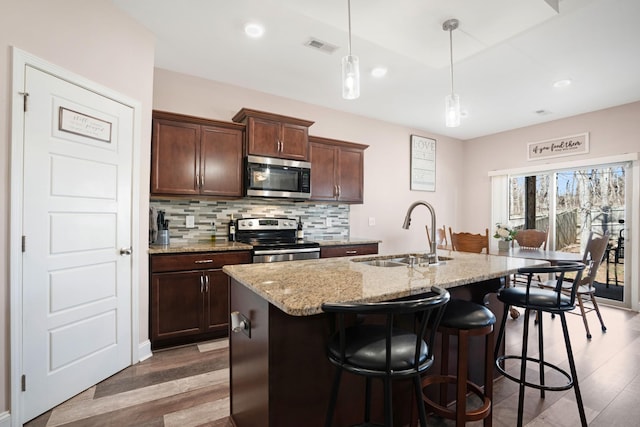 kitchen featuring a sink, stainless steel appliances, backsplash, and wood finished floors