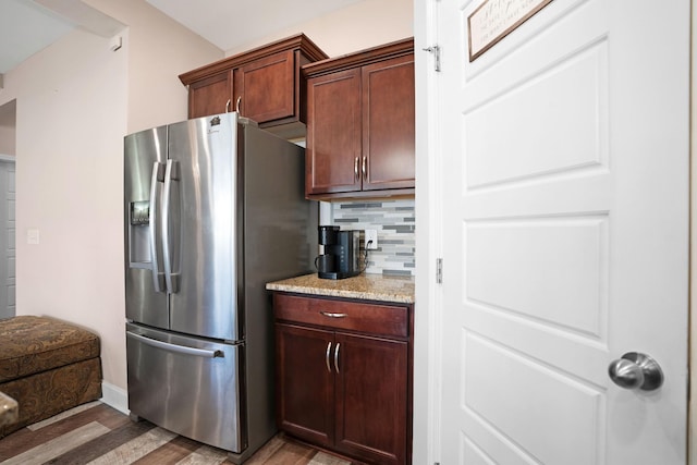 kitchen featuring decorative backsplash, stainless steel fridge, light stone countertops, and light wood finished floors