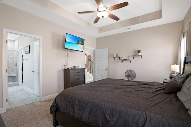 carpeted bedroom with visible vents, a raised ceiling, baseboards, and ensuite bathroom