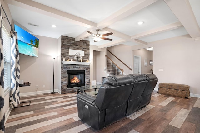 living room with wood finished floors, baseboards, visible vents, beam ceiling, and a stone fireplace