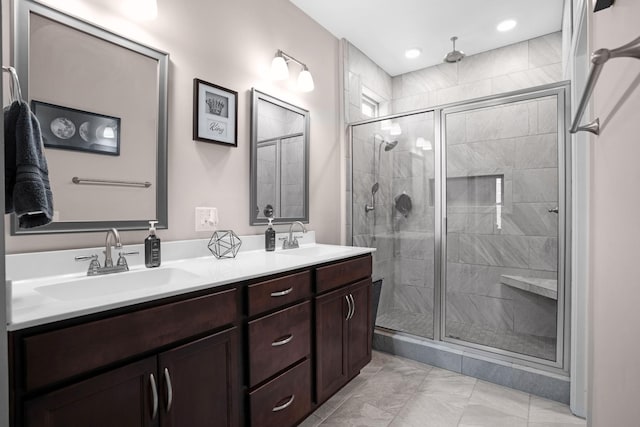 bathroom featuring a shower stall, double vanity, marble finish floor, and a sink