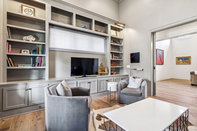 living room with light wood-style floors, built in features, and baseboards