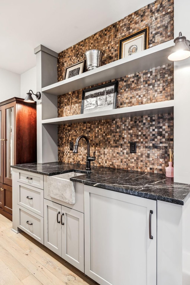 bar with a sink, light wood-style flooring, and decorative backsplash