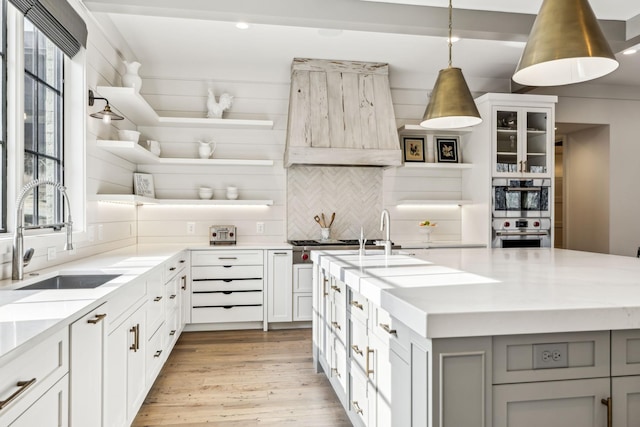 kitchen featuring white cabinetry, light stone countertops, open shelves, glass insert cabinets, and pendant lighting