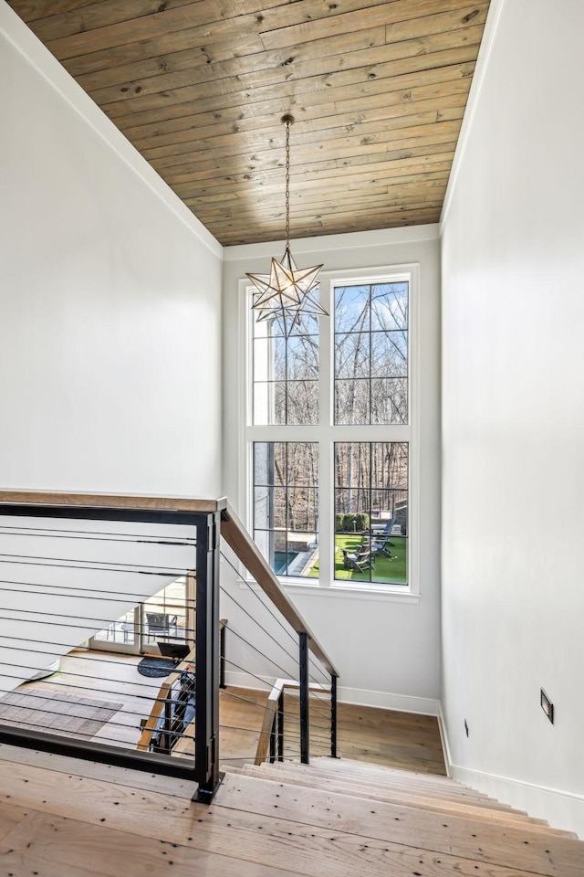 staircase featuring crown molding, hardwood / wood-style flooring, wood ceiling, and a healthy amount of sunlight