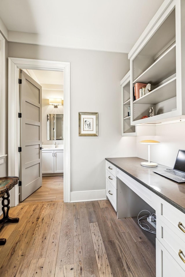 office space with baseboards, a sink, and light wood-style floors