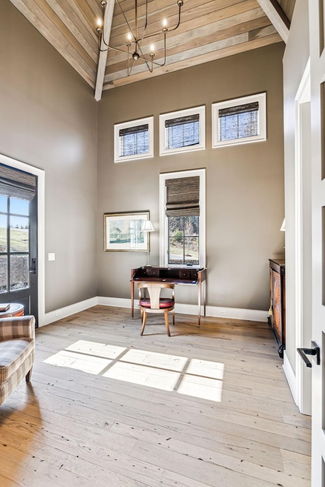 interior space with baseboards, light wood-style flooring, and a high ceiling