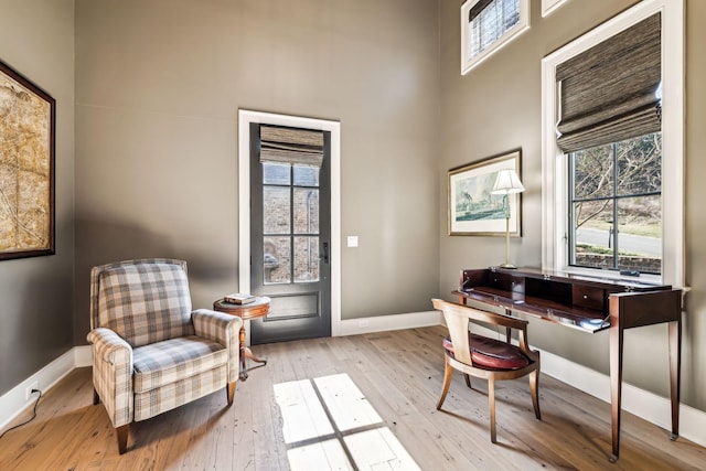 office area with a high ceiling, a healthy amount of sunlight, light wood-style flooring, and baseboards