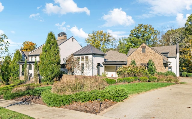 view of front of home featuring a standing seam roof, a chimney, and metal roof