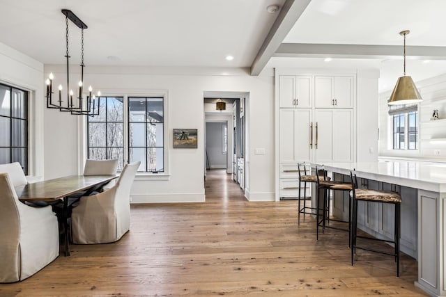 dining room with recessed lighting, hardwood / wood-style floors, a chandelier, beamed ceiling, and baseboards