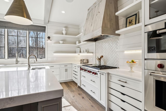 kitchen featuring light countertops, appliances with stainless steel finishes, custom exhaust hood, and white cabinetry