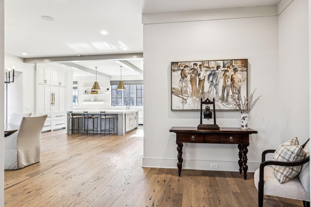 interior space with baseboards, beamed ceiling, recessed lighting, and light wood-style floors