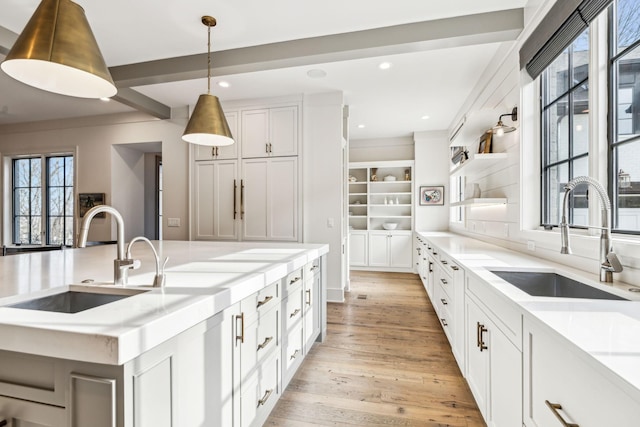 kitchen with a sink, light countertops, open shelves, and white cabinets