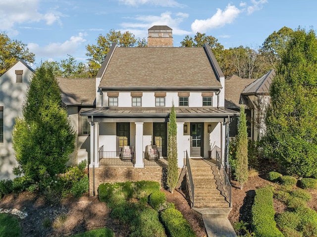 view of front of property with covered porch, metal roof, a standing seam roof, and a chimney