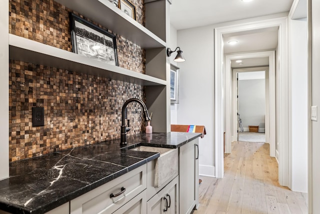 kitchen with light wood-style flooring, a sink, white cabinetry, open shelves, and tasteful backsplash