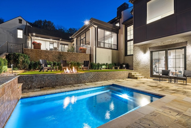 pool at twilight featuring a patio area and a fire pit