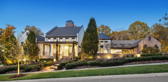 view of front of home with a porch, a chimney, and stairs