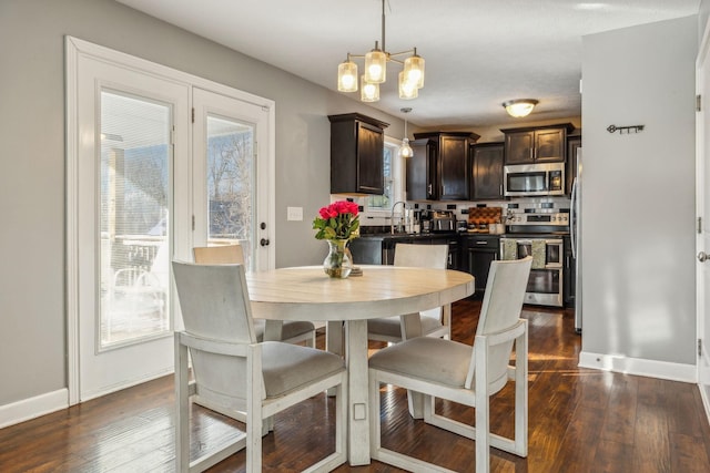 dining area featuring an inviting chandelier, baseboards, and dark wood finished floors