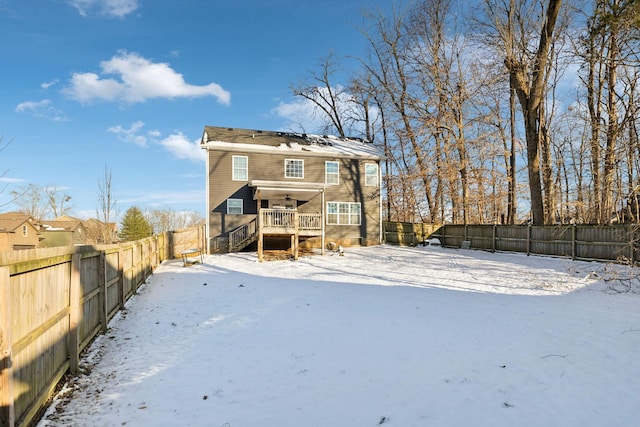 snow covered house featuring a fenced backyard and stairs