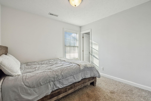 bedroom with a textured ceiling, carpet, visible vents, and baseboards