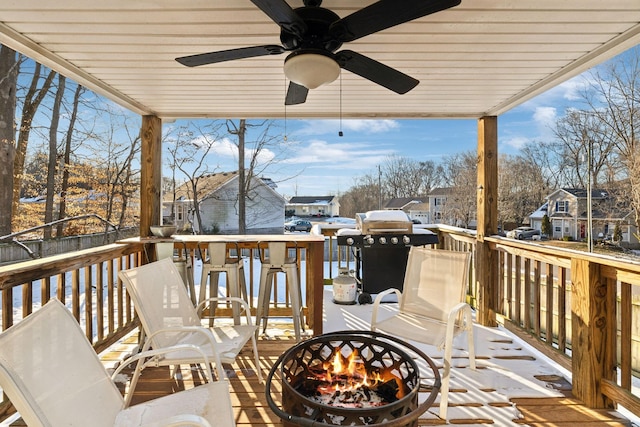 wooden deck featuring a ceiling fan, a residential view, and a fire pit