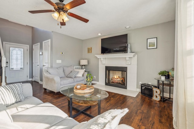 living area with a ceiling fan, baseboards, wood finished floors, and a tile fireplace