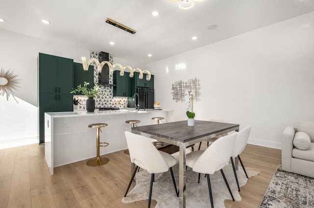 dining room featuring baseboards, recessed lighting, and light wood-style floors