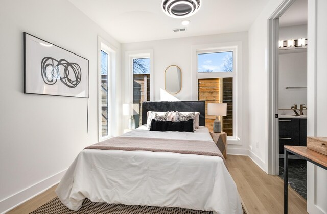 bedroom featuring visible vents, light wood-style flooring, and baseboards