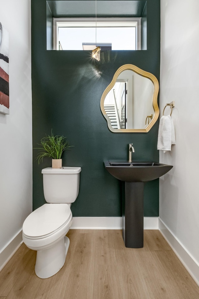 half bathroom with a healthy amount of sunlight, toilet, and wood finished floors